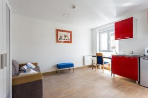 uma cozinha e sala de estar com armários vermelhos e cadeiras azuis em CMG Porte de Châtillon - Malakoff V em Malakoff