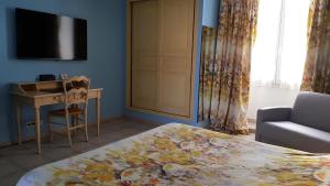 a bedroom with a bed and a desk and a television at Hôtel Les Palmiers in Saint-Tropez