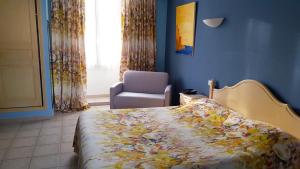 a bedroom with a bed and a chair and a window at Hôtel Les Palmiers in Saint-Tropez