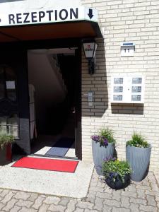 a entrance to a building with a red rug and two plants at Hotel Calenberger Hof in Wennigsen