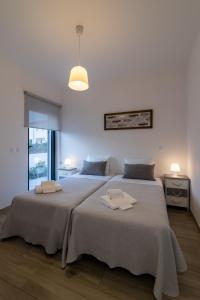una camera da letto con due letti con asciugamani sopra di Biscuttela Vicentina a Praia da Arrifana Altre 82 foto