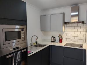 eine Küche mit einer Spüle und einer Mikrowelle in der Unterkunft 1 WATER PUMP HOUSE in Bury Saint Edmunds