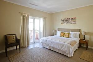 een slaapkamer met een bed, een raam en een stoel bij Villa Costa Rose - No Loadshedding in Kaapstad