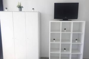 a white book shelf with a tv on top of it at Komplett ausgestattetes Apartment in Dormagen in Dormagen