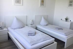 2 Betten in einem weißen Zimmer mit Kissen darauf in der Unterkunft Komplett ausgestattetes Apartment in Dormagen in Dormagen