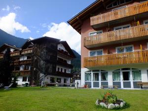 two apartment buildings with a lawn in front of them at Hotel Garni Al Nardis in Carisolo