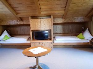 a room with two beds and a table and a tv at Ferienhaus am Höldersberg in Sonthofen