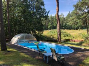 a swimming pool with two chairs and a tent at Wooden House&Pool in Osowa
