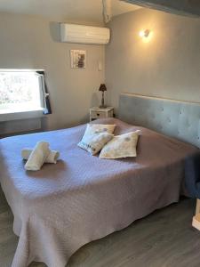 een slaapkamer met een bed met kussens erop bij Petit studio Le Pigeonnier à 5 mn de Lourmarin in Puyvert