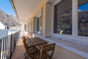 a balcony with a wooden table and chairs at Appartement Terrasse - Télécabine 2min - Thermes 4min - Tout équipé in Cauterets