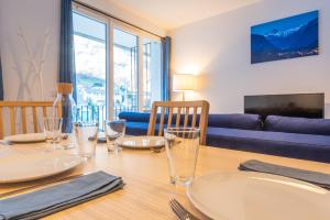a dining room table with plates and glasses on it at Appartement Terrasse - Télécabine 2min - Thermes 4min - Tout équipé in Cauterets