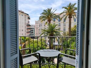 d'un balcon avec une table, des chaises et des palmiers. dans l'établissement Hôtel de Provence, à Cannes