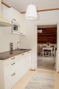 uma cozinha com armários brancos e uma sala de jantar com uma mesa em Wiedemanni Apartment em Haapsalu