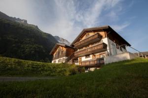 un grande edificio in legno su una collina con una montagna di Hotel Bergführer a Elm