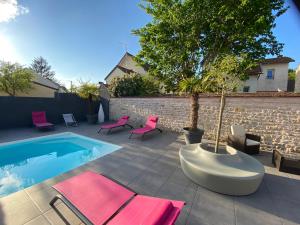 un patio con sillas rosas y una piscina en Logis L'Hôtel D'Arc, en Arc-sur-Tille