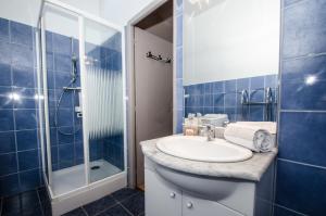 La salle de bains est pourvue de carrelage bleu, d'un lavabo et d'une douche. dans l'établissement Résidence Androsace, à Chamonix-Mont-Blanc