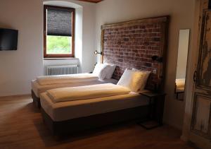 2 Betten in einem Zimmer mit Ziegelwand in der Unterkunft Pension Leano in Nötsch