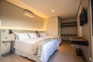 NAIM Hotel في كابيتوليو: غرفة فندقية بسرير كبير وتلفزيون بشاشة مسطحة