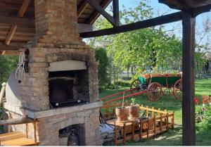 a stone fireplace with a cart in a yard at Под старата липа in Goritsa