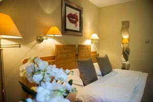 Cette chambre d'hôtel comprend un lit avec des draps blancs et des fleurs. dans l'établissement Le Moulin de la Walk, à Wissembourg