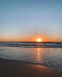 a sunset on the beach with the ocean at Cabañas Kundalini Punta del Diablo in Punta Del Diablo