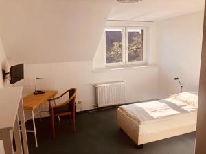 Schlafzimmer mit einem Bett, einem Schreibtisch und einem Tisch in der Unterkunft Gästehaus Schlossgarten in Etelsen