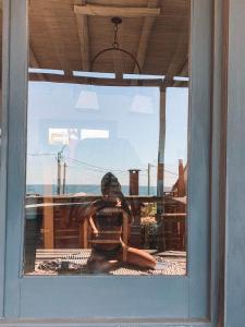 a reflection of a woman sitting in a window at Cabañas Kundalini Punta del Diablo in Punta Del Diablo