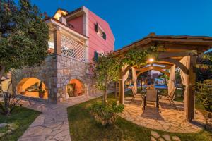an outdoor patio with a pergola and a pink building at Villa Garden Star in Zakynthos Town