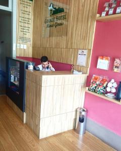 a man sitting at a counter talking on a cell phone at Grande Hotel Minas Gerais in Siqueira Campos