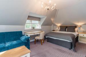 een slaapkamer met een bed, een bank en een stoel bij Gorse Hill Hotel in Woking