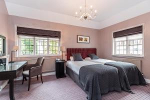 a bedroom with a bed and a desk and windows at Gorse Hill Hotel in Woking