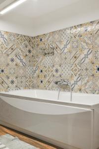 uma banheira na casa de banho com uma parede de azulejos em Filomena Suite Luxury Apartment em Catânia