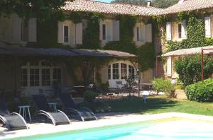 a house with chairs and a pool in front of it at Logis Hôtel Restaurant La Sommellerie in Châteauneuf-du-Pape