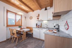 una cocina con armarios blancos y una mesa con sillas. en Pineiderhof, en Funes