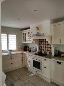 a kitchen with white cabinets and a stove top oven at Maison au pied des ocres in Roussillon