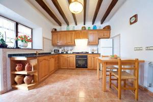 a kitchen with wooden cabinets and a table and a table and chairs at Villa Mosson in Port de Pollensa