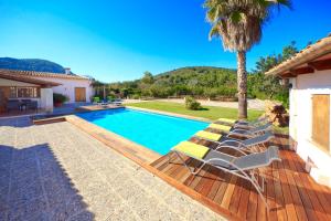 a swimming pool with lounge chairs and a palm tree at Villa Fullos by Sealand Villas in Pollença