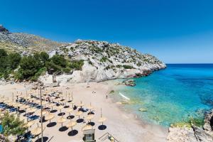 a beach with chairs and umbrellas and the ocean at Villa Fullos by Sealand Villas in Pollença