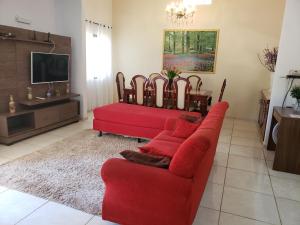 a living room with a red couch and a tv at Angel Family Houses in Foz do Iguaçu