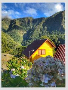 une maison jaune avec une montagne en arrière-plan dans l'établissement Pousada Bugio da Serra, à Novo Horizonte