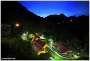 a small yellow house with lights on a hill at night at Pousada Bugio da Serra in Novo Horizonte