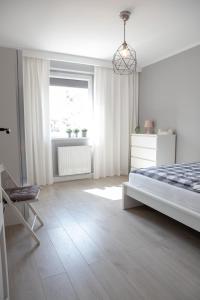 a white bedroom with a bed and a window at Apartament Scandic in Malbork