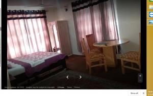 um quarto com uma cama, uma mesa e cadeiras em Gilgit Deosai Executive Guest House em Gilgit