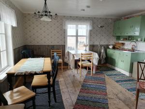 uma cozinha e sala de jantar com armários verdes e uma mesa em Huset Alvina em Korsnäs