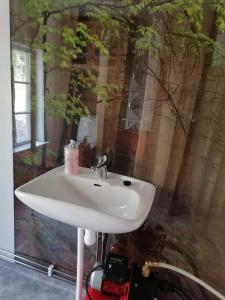 a white sink in a bathroom with a tree mural at Huset Alvina in Korsnäs
