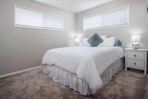 a white bedroom with a bed and two windows at Walnut Bungalow East in Hillsboro