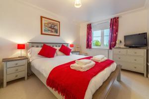 a bedroom with a bed with red pillows and a tv at Blue Horizon in Carbis Bay