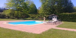 a pool with chairs and a table and a house at Villa El tinganon in Llanes