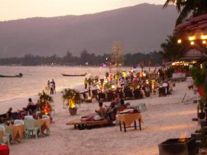 un grupo de personas sentadas en una playa por la noche en Nantra Chaweng Beach Hotel en Chaweng