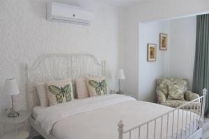 a white bedroom with a bed and a chair at Villamer Alaçatı in Alaçatı